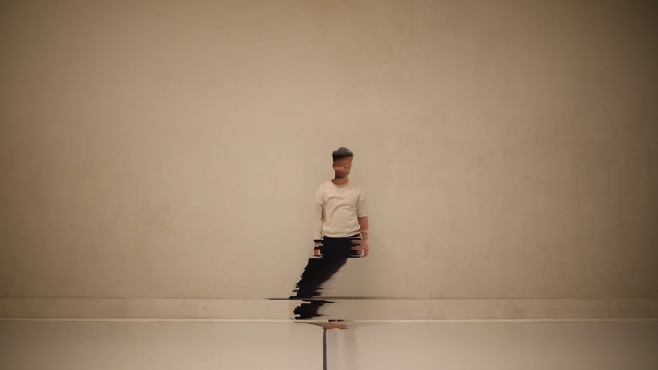 A lone performer fragmented by a digital glitch against a pale wall.